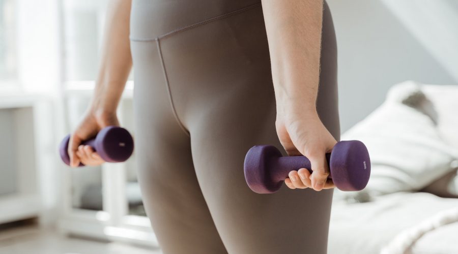 person wearing gray leggings exercising using dumbbells