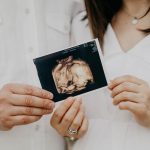 couple holding ultrasound picture of baby