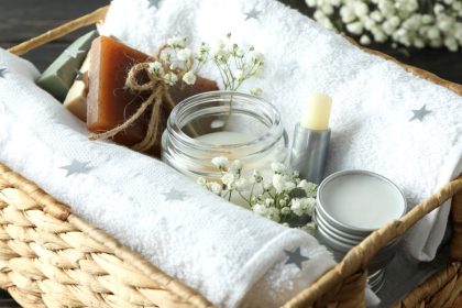 A wicker basket containing a variety of gifts from a candle, homemade chapstick, towels, and a homemade bar of soap.