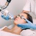 A woman sitting in a medical spa chair receiving a facial laser treatment. She's wearing protecting eyewear.