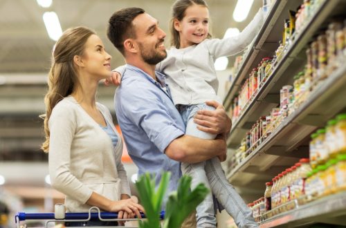 A young family—a father, mother, and daughter—shopping for essential grocery items at the store together.