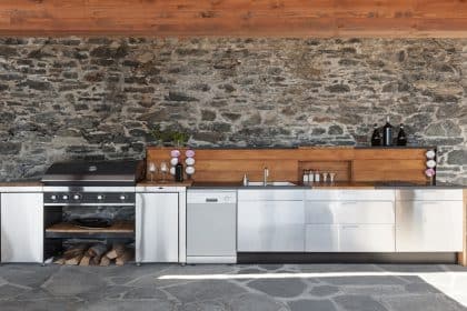 Several kitchen appliances are against a wall. There are long, cylindrical lights hanging down on either side of the kitchenware.