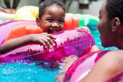 A close-up of a mother and daughter floating in a swimming pool while sitting in colorful inflatable tubes.