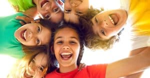 A group of kids huddled together, smiling down at the camera from above, with the light shining behind them.