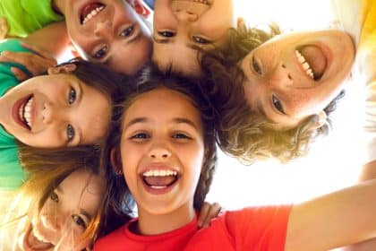 A group of kids huddled together, smiling down at the camera from above, with the light shining behind them.