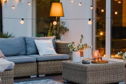 A close-up of an outdoor living space with string lights, an outdoor sofa, a coffee table, cushions, plants, and candles.